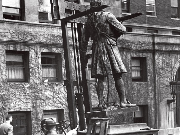 Historic photo of workers installing a sculpture of Alexander Hamilton on Columbia campus, outside Hamilton Hall