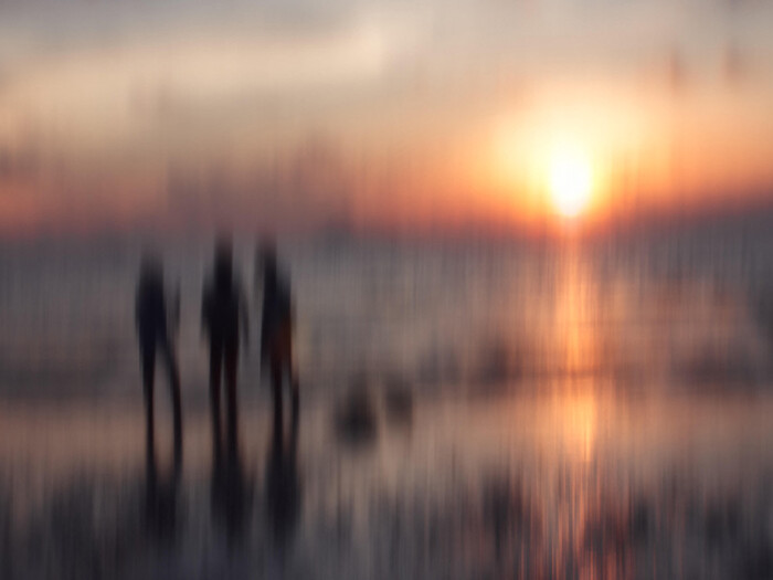 hazy photo of three figures on a beach